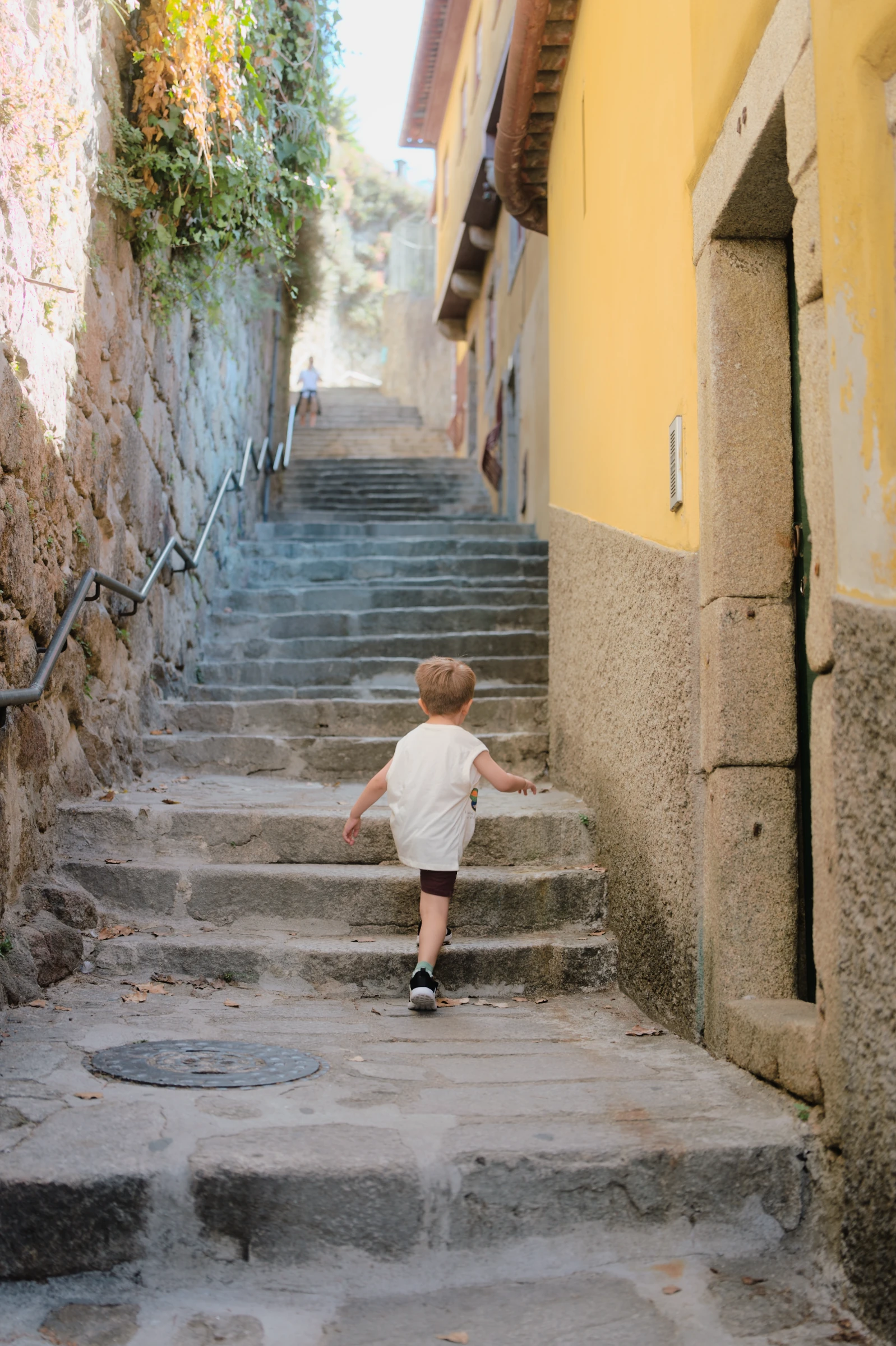 A small figure seen from behind walking up a narrow stone street